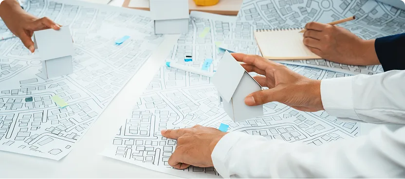 Hands holding house models over city maps